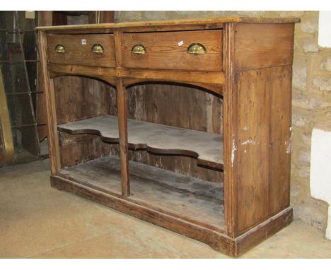 A rustic stripped pine kitchen dresser base fitted with two frieze drawers over an open shaped shelf and boarded base, 132 cm