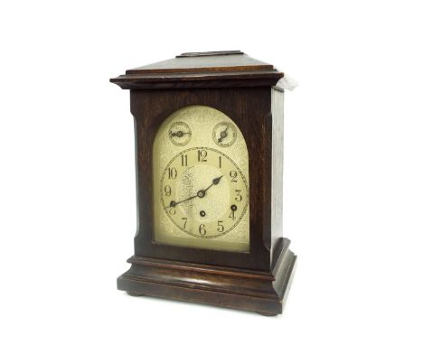 German oak three train mantel clock, the movement striking on five rods, the 7" silvered arched dial with subsidiary slow/fas