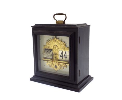 Ebonised mantel ticket clock, the 6.5" square dial with apertures for digital hours and minutes, within an ornate gilt metal 