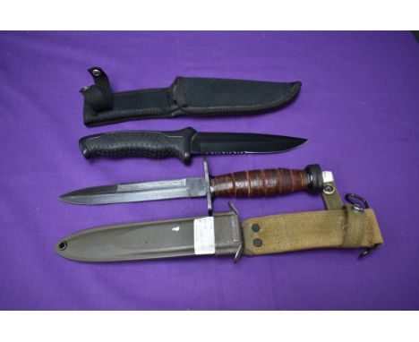 A Made in China Fighting Knife with rubberized grip and canvas scabbard, overall length 28cm along with a made in China Copy 