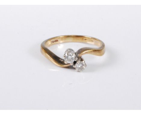 A 9ct gold two stone diamond ring, the two round brillinat cut diamonds, total estimated approx. 0.20cts, in a crossover styl