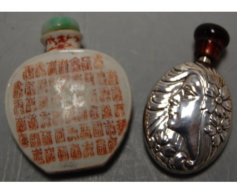 A white metal scent bottle embossed to both sides with profile portrait of a maiden and flowers having faux amber cap, togeth