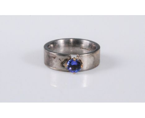 A silver and tanzanite ring, the round tanzanite, approx. 5mm diameter, claw mounted to a plain 6mm wide band, stamped 925 wi