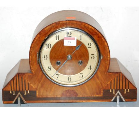 An Art Deco walnut cased mantel clock, having a silvered dial with Arabic numerals, and eight day movement