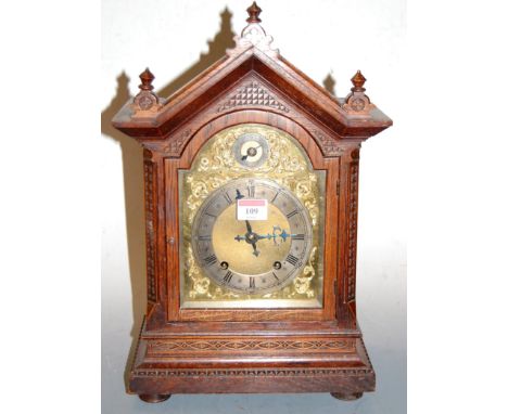 A late 19th century Continental oak cased mantel clock having an arched brass dial with silvered chapter ring, Roman numerals