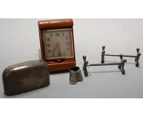 A pair of silver plated cutlery rests, silver hip flask sleeve, leather cased bedside alarm clock, etc