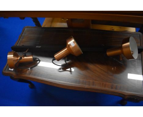 A vintage lighting track with three copper effect spots