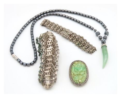 A Chinese carved jade brooch set in silver, 9.5g, 36.5mm high, two Asian white metal bracelets 59.9g & a hematite necklace wi