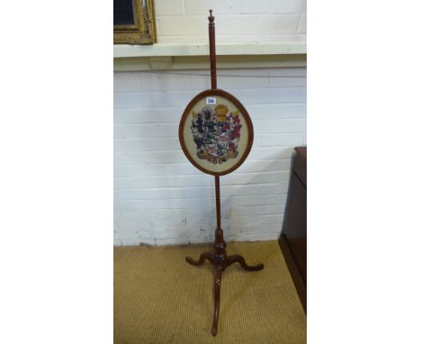 A 19th century mahogany fire screen with an Armorial hand stitched crest on a tripod base