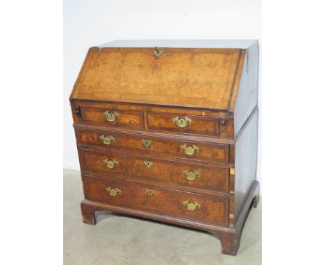 A Queen Anne/George I walnut bureau with a fitted interior above two small and three long graduating drawers on bracket feet 