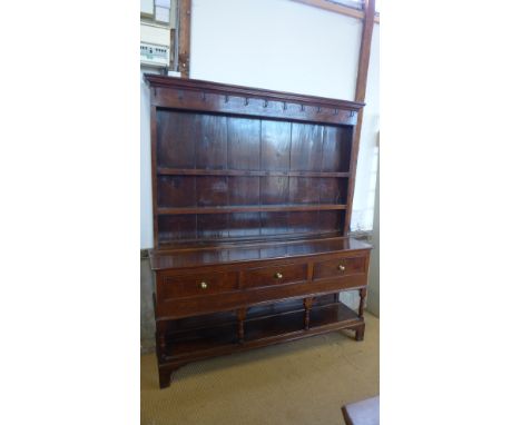 A 20th century oak dresser with a 19th century top, the panelled and shelved upper structure with moulded cornice, the lower 