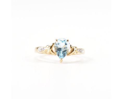 A hallmarked blue topaz and diamond ring. The ring set with a central blue pear cut topaz flanked by diamond set shoulders to
