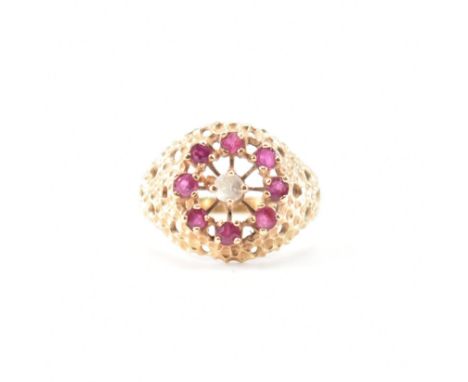 A hallmarked 9ct gold ruby and white stone ring. The ring having a round head with a central white stone with a halo of round