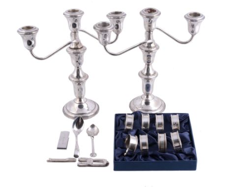  A pair of silver coloured three light candlesticks,   stamped Sterling, with bell shaped capitals, turned stems and on circu