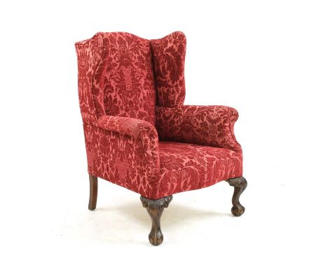 A George III style mahogany framed wingback armchair, circa 1900, upholstered in a red damask fabric, on carved ball and claw