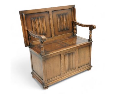 Late 20th century oak monk's bench, hinged and sliding back with linenfold decoration, hinged box seat, on turned bun feet Di