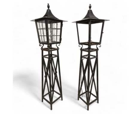 Pair of 20th century wrought metal garden lanterns on stands, the square tapering lantern with finial top, enclosed by hinged