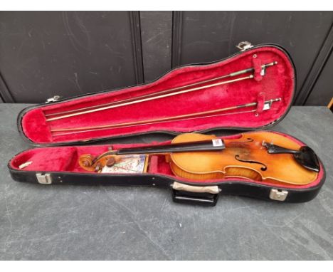 An antique Continental violin, labelled 'Antonius Stradivarius', with 14in two-piece back, with two bows, in padded case.