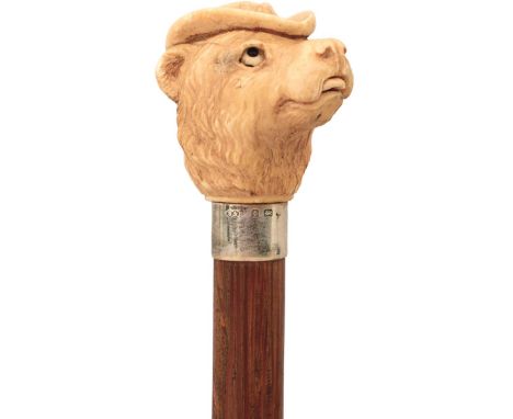 A LATE 19TH/EARLY 20TH CENTURY ARTICULATED WALKING CANE, the ivory handle carved as the head of a dog wearing a hat, a button