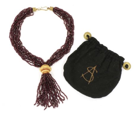 A gold and silver, garnet tassel necklace, by Sandra D'Auriol, with ten rows of garnet beads, gathered to a tassel with a gol