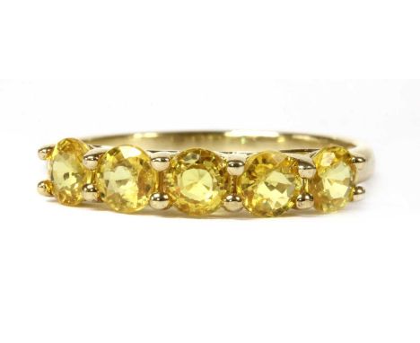 A gold five stone yellow sapphire ring, a row of circular mixed cut yellow sapphires, claw set to an open gallery and a plain