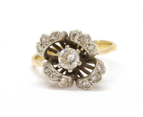 A diamond cluster ring, a brilliant cut diamond claw set to the centre, to surround of off-set curved collets, with eight cut