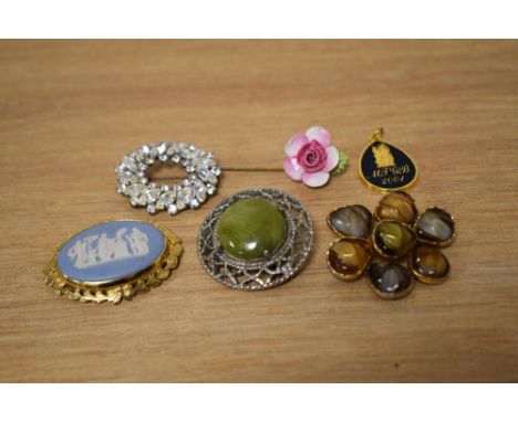 A collection of costume brooches, including a Wedgwood brooch in a decorative mount, a floral stick pin and paste set example