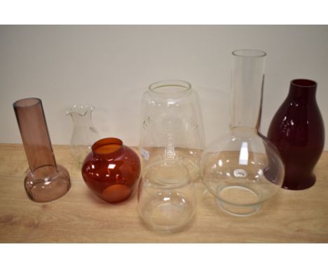 An assorted collection of clear and coloured glass oil lamp shades and chimneys, including a lighthouse 'It Won't Go Out' sha