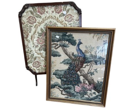 A large cross stitch peacock in a frame along with a fire-screen that converts into an occasional table with jacquard fabric 