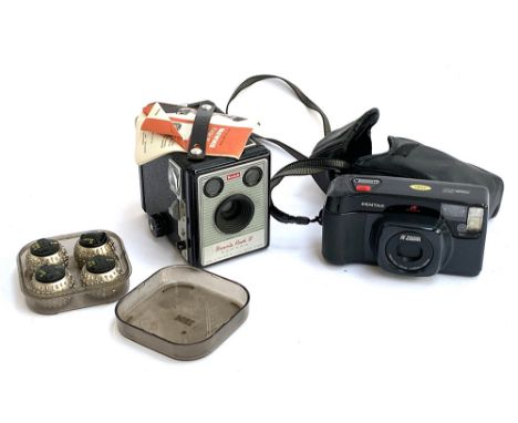 A Kodak Brownie Flash III box camera; a Pentax 35mm camera; and a set of IBM golfball typewriter balls, in various fonts 
