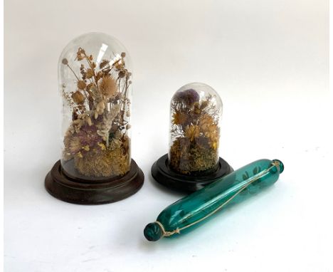 Two glass cloches on turned wooden bases each with a  dried floral arrangement, 30cmH and 21cmH; together with a green glass 