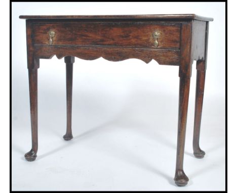 An 18th century oak lowboy side table being raised on simple turned, tapering legs with pad feet. Above a fitted frieze wth s