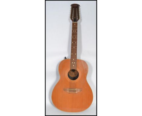 A vintage 20th century Encore 12 string guitar. The twelve strings having mother of pearl tuning pegs. The shaped body having
