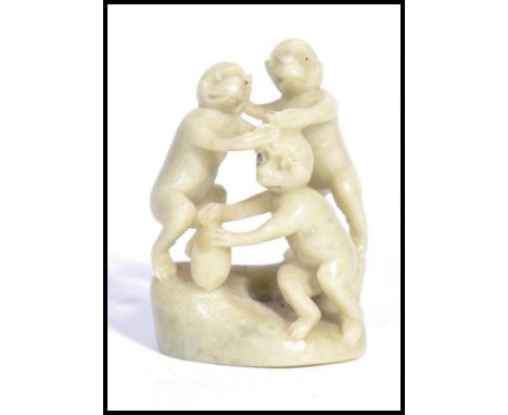 A Chinese unusual carved one piece soapstone jade coloured diorama carving of three monkeys on plinth. Measures 6 cm high.