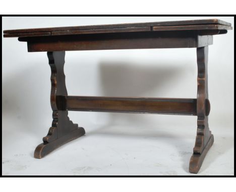 A 1930's oak draw leaf refectory dining table being raised on lyre shaped supports with stretcher having extending top above.