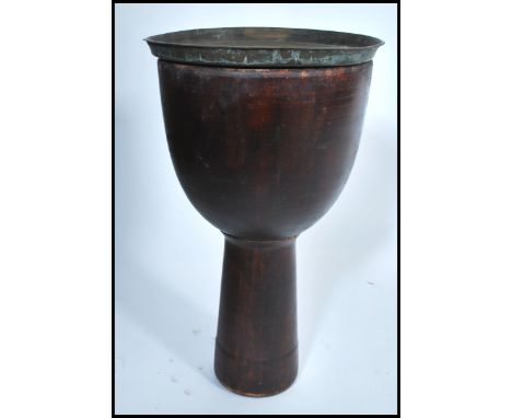 A 20th century side table in the form of a tribal drum with a brass Anglo Indian top.&nbsp;Measures 64cm tall.