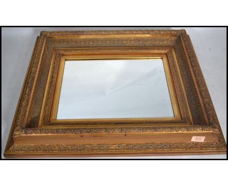 An early 20th century wall mirror having an ornate gilt stepped frame. The central bevelled glass panel of rectangular form.