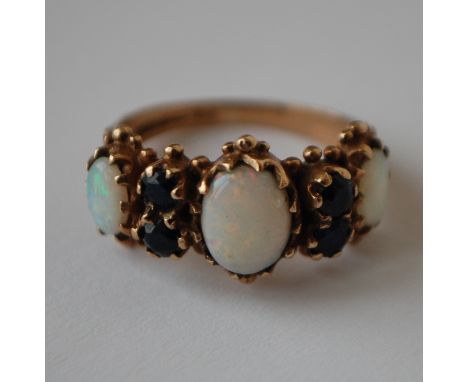 A hallmarked 9ct gold opal and sapphire ring set with three graduated oval cut opal flanked by four round cut blue sapphires 
