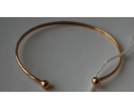 A hallmarked 9ct gold bangle with ball finials. Hallmarked Birmingham. Weight 2.5g.