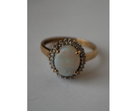 A hallmarked 9ct gold ring set with a central opal surrounded by a diamond halo. Diamonds approx 20pts. Hallmarked Birmingham