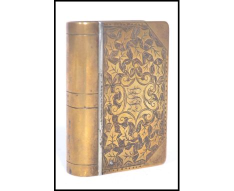 A 19th century Victorian brass snuff box in the form of a book having an engraved leaf design with monogrammed armorial shiel