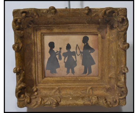 A 19th century Victorian silhouette cut out pictures depicting a group of three children playing with doll , hoopla etc. Fram