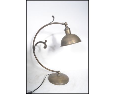 A 20th century art deco style brushed metal desk lamp having a curved arm with scroll work decoration and pendant shade on a 
