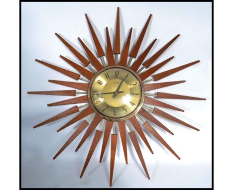 A vintage mid century teak wood sunburst wall clock. The gilded dial with roman numeral chapter ring having stunning teak sun
