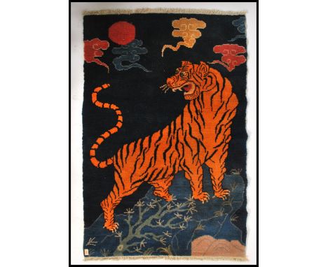 An early 20th century Tibetan tiger rug.&nbsp; The blue ground with large central tiger&nbsp; chasing swirling clouds and tas