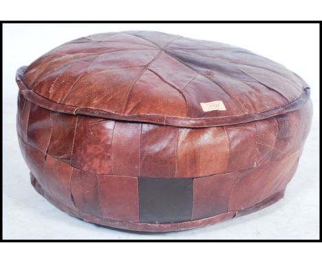 A vintage mid century leather footstool pouffe of barrel form with patchwork leather upholstery, all of believed Moroccan for