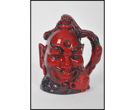 A Royal Doulton flambė character jug depicting Aladdin's Genie D6971 , handle modelled on a genie's lamp and smoke, within a 