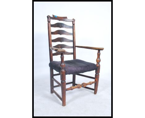 A 19th Georgian elm wood North Country carved armchair. The wavey ladder back armchair raised on bobbin turned legs united by