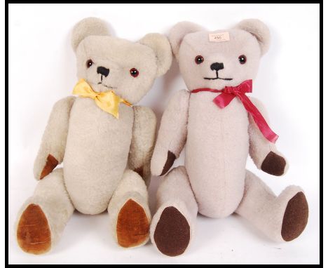 A pair of vintage mid 20th century teddy bears being made in Bristol having glass eyes with coloured bows.
