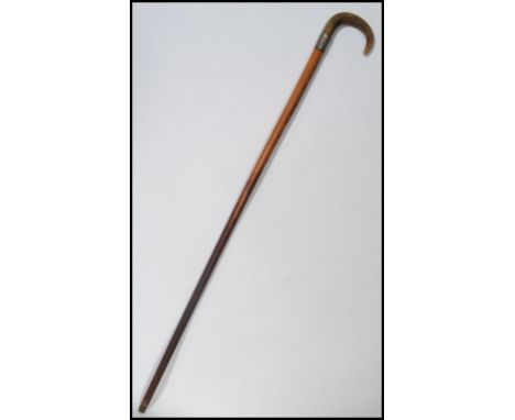 A 19th century Victorian walking stick cane having a tapering wooden shaft with shaped horn handle. The silver collar having 